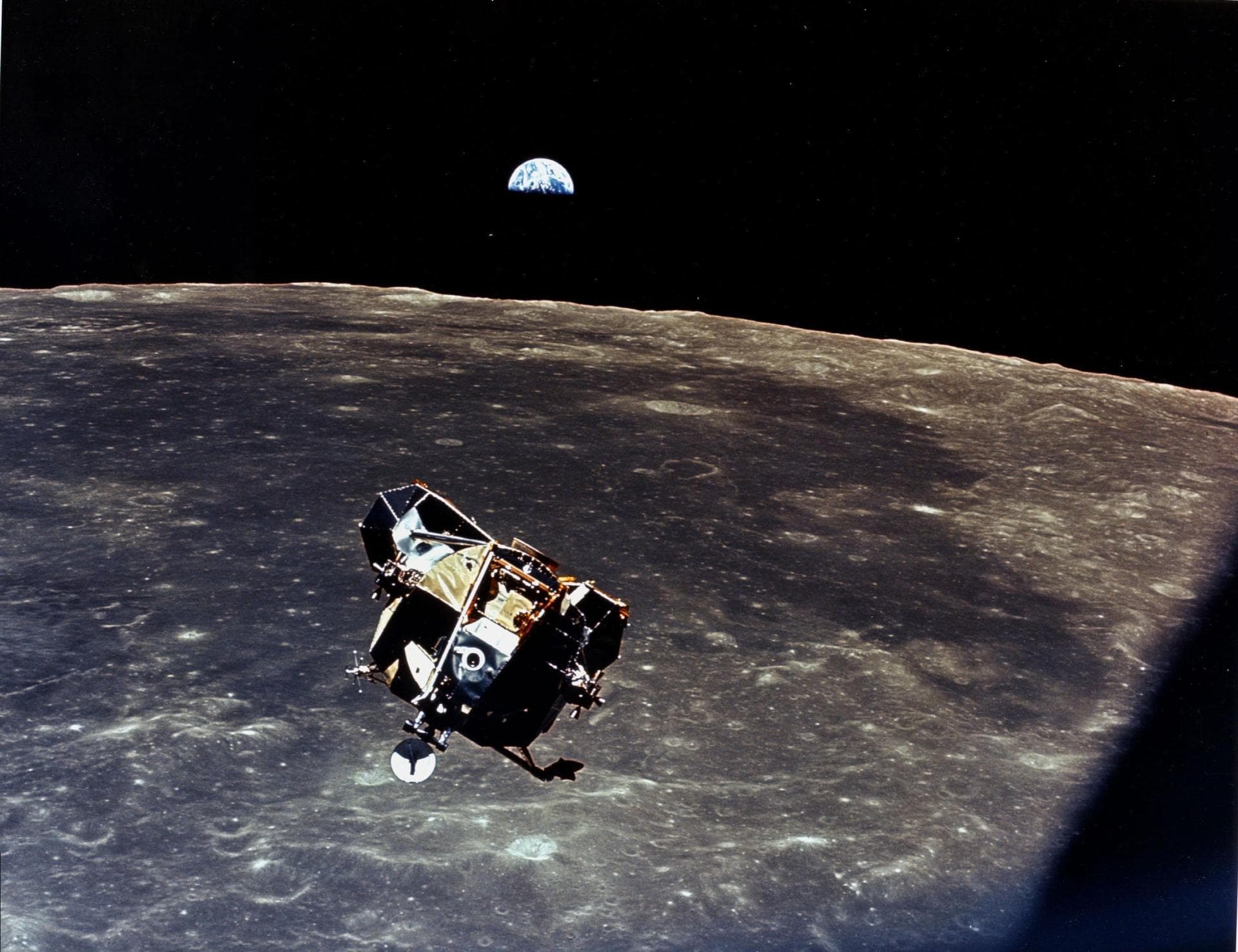 The lunar module Eagle ascending above the Moon with Earth rising beyond the horizon